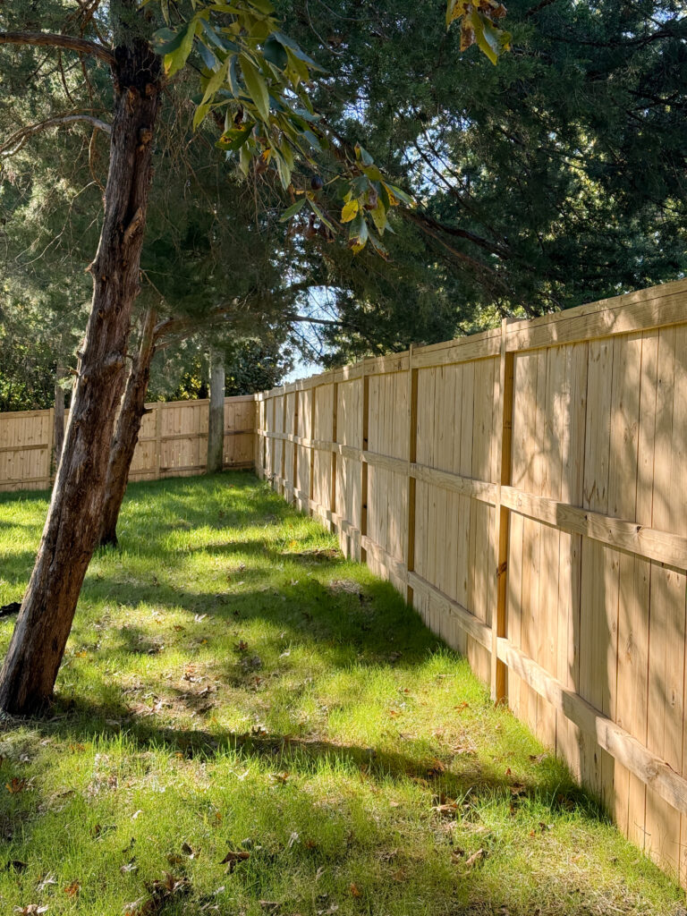 Wood privacy fence seen from the corner, running straight along the property line with an even gap at the ground.