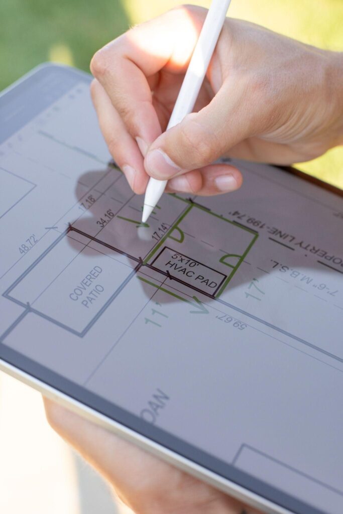 Close-up of a digital fence layout being sketched on a tablet with a stylus, showing detailed property and patio measurements.