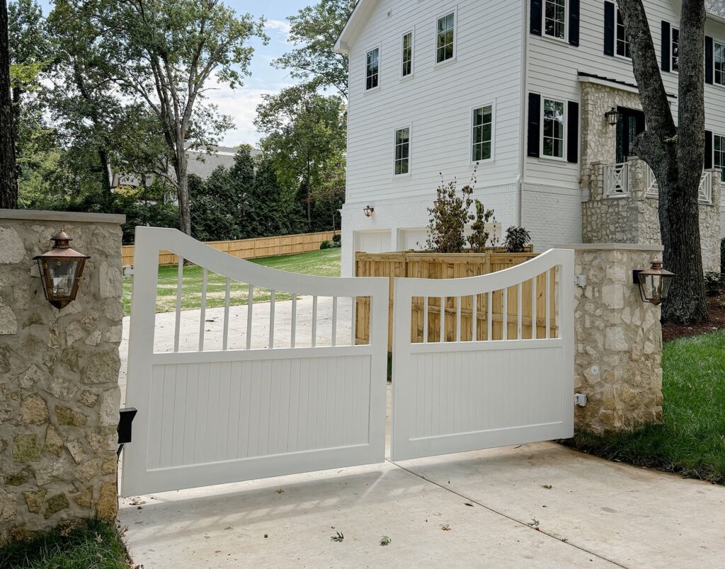 White double swing driveway gate with stone columns in Middle Tennessee.