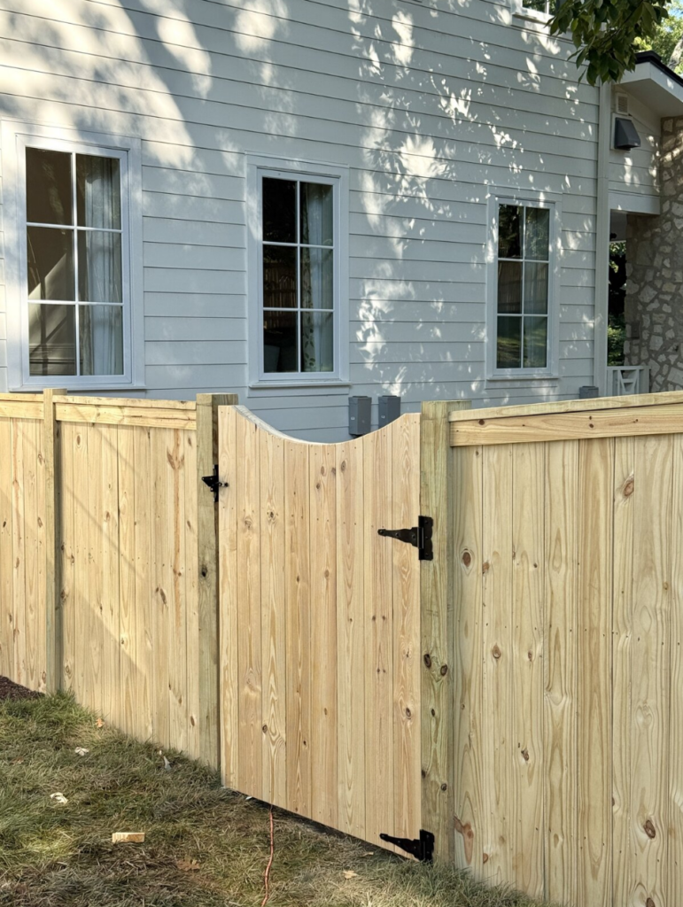 Custom wood privacy fence and curved-top gate installation by Heron Building Co.